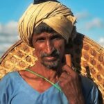 Man Holding Black and White Goat Under Blue and White Sky